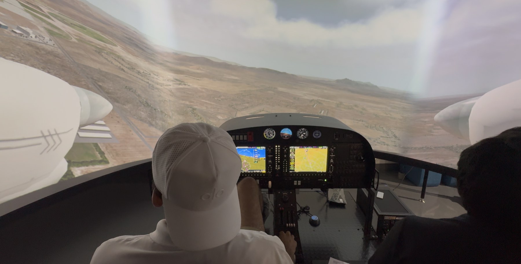 FAA-approved Diamond DA40/DA42 flight simulator — pilot and instructor at the wraparound visuals and G1000 glass cockpit