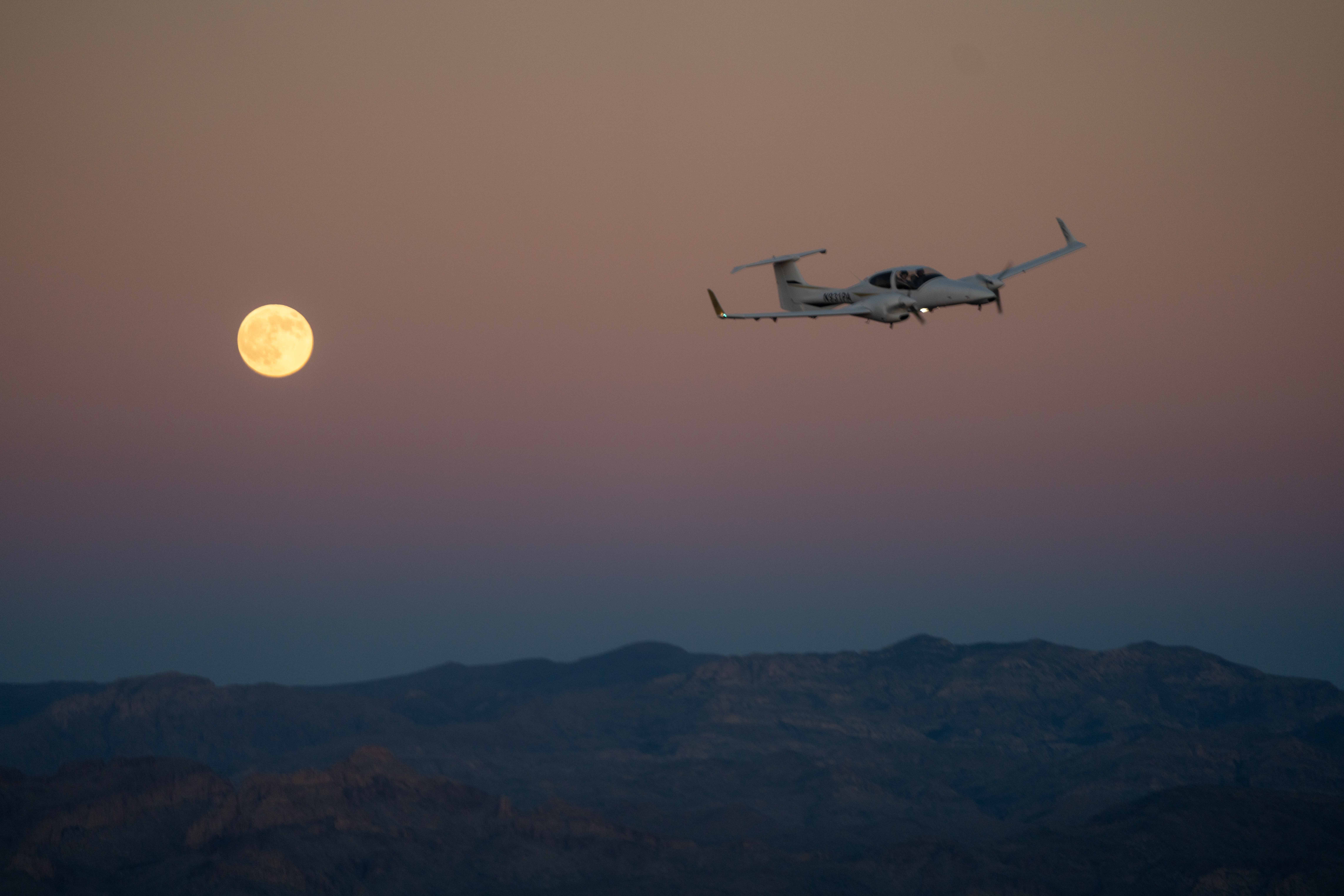 Diamond DA42 in flight at dusk with full moon