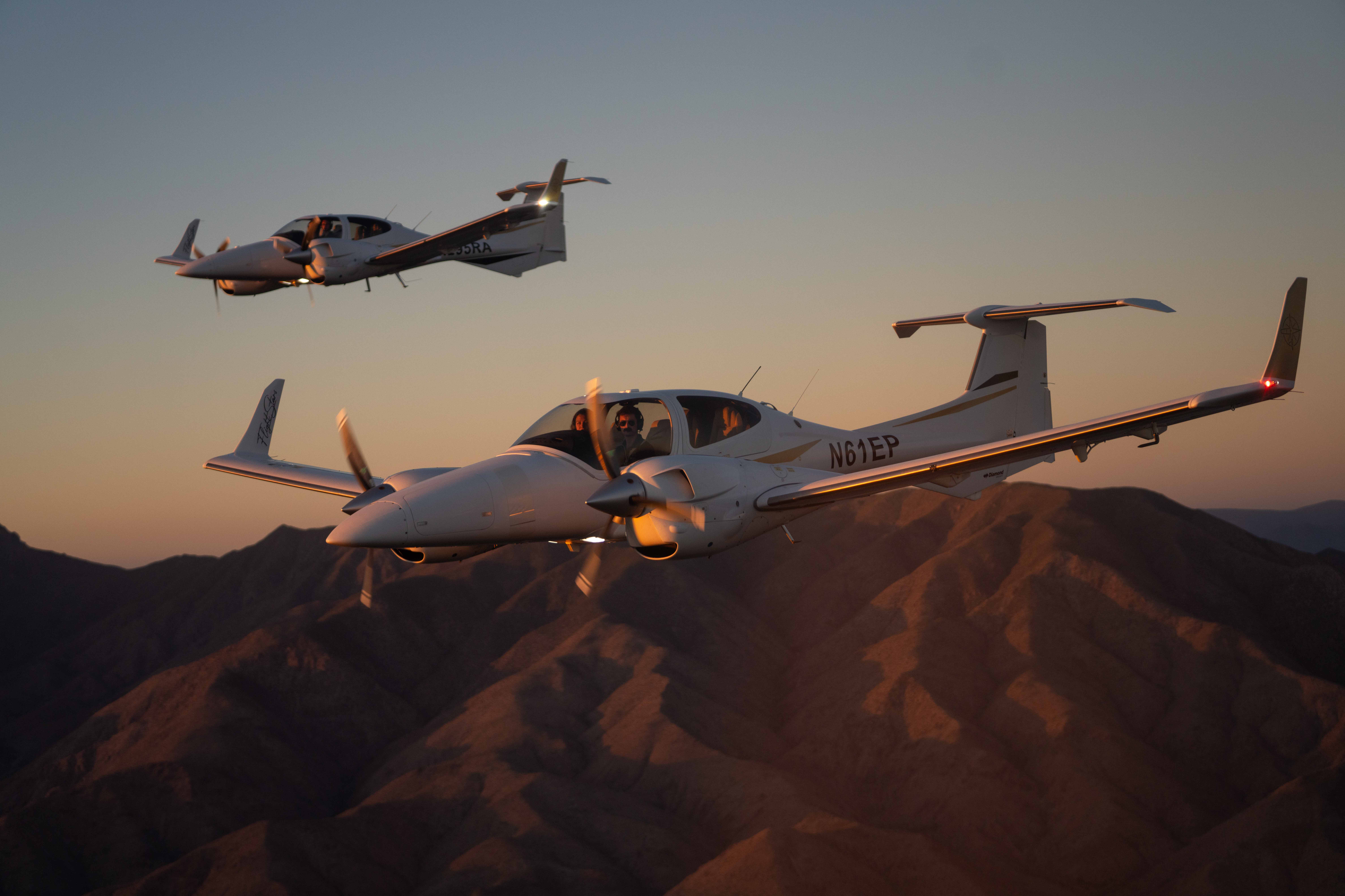 Two Diamond DA42s in formation over the mountains at sunset
